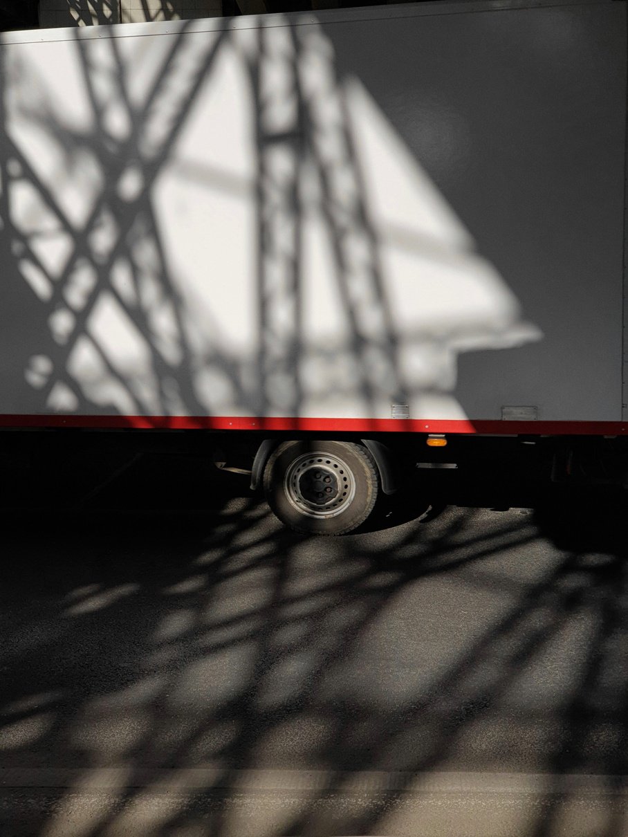 Street image: the shadow of a truck on the side of a building