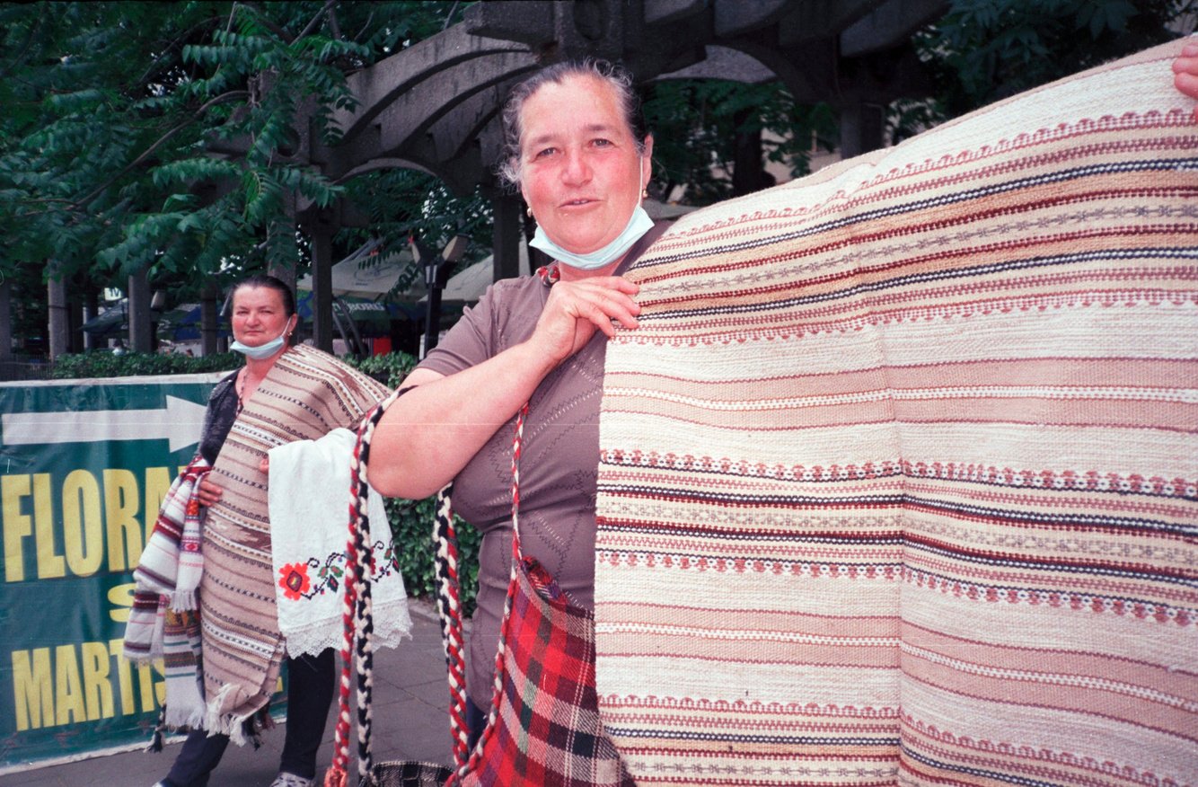 A portrait of a street merchant in Bucharest selling handmade rugs.