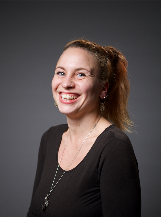 a smiling person in a black shirt and necklace