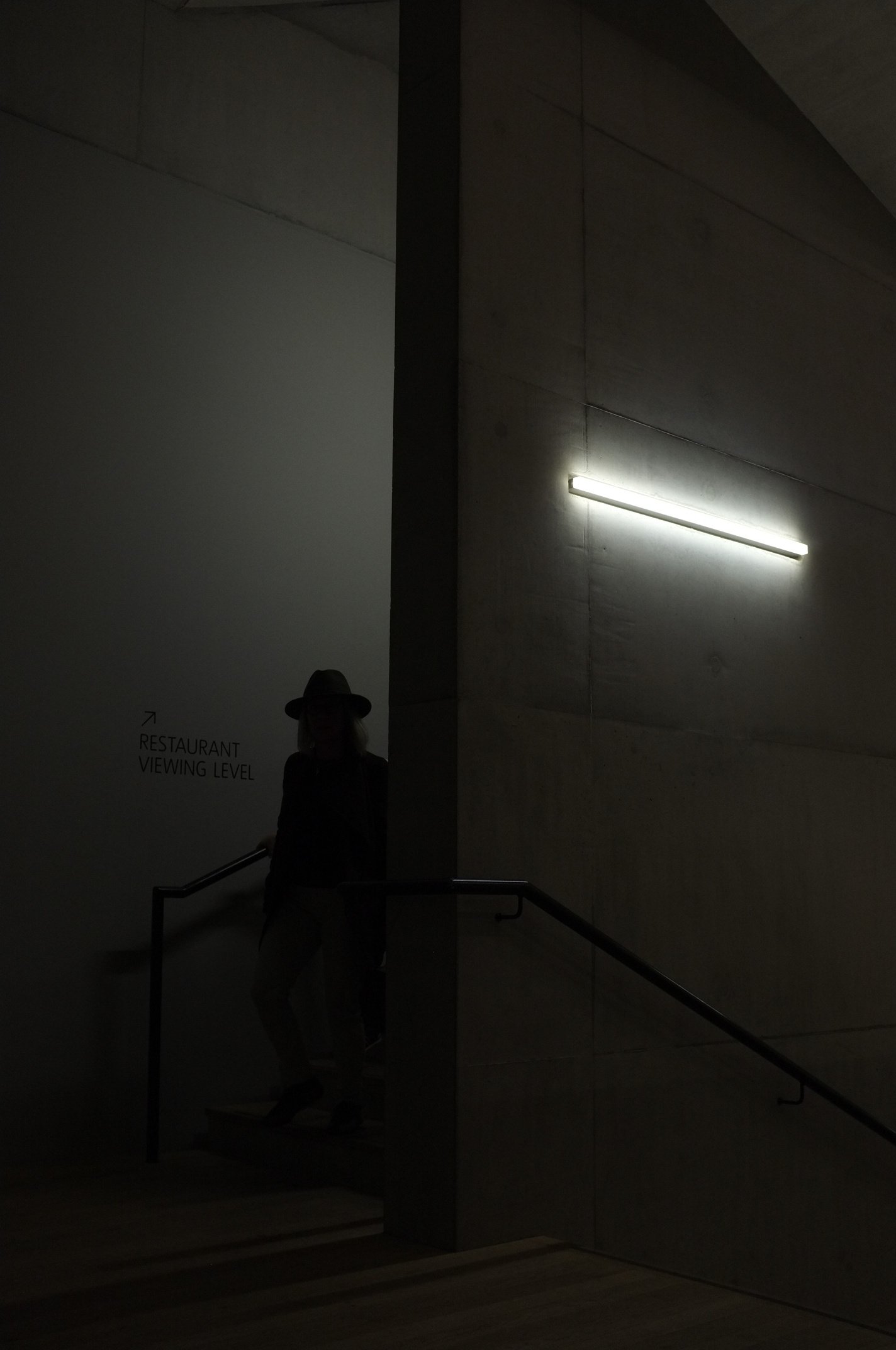 Moddy black and white street portrait of a person on a dark staircase.