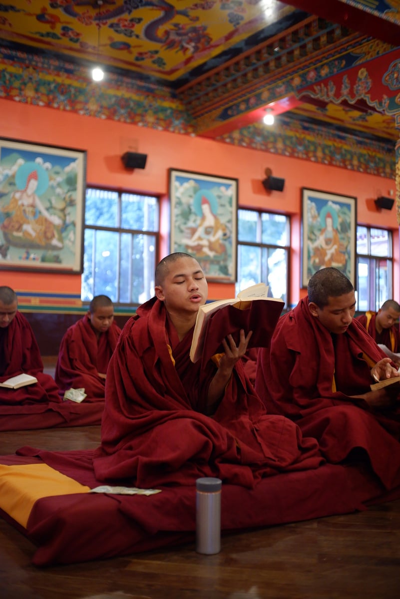 Tibetan Buddhist Monk reading prayers during ritual at a monastery in Kathmandu, Nepal