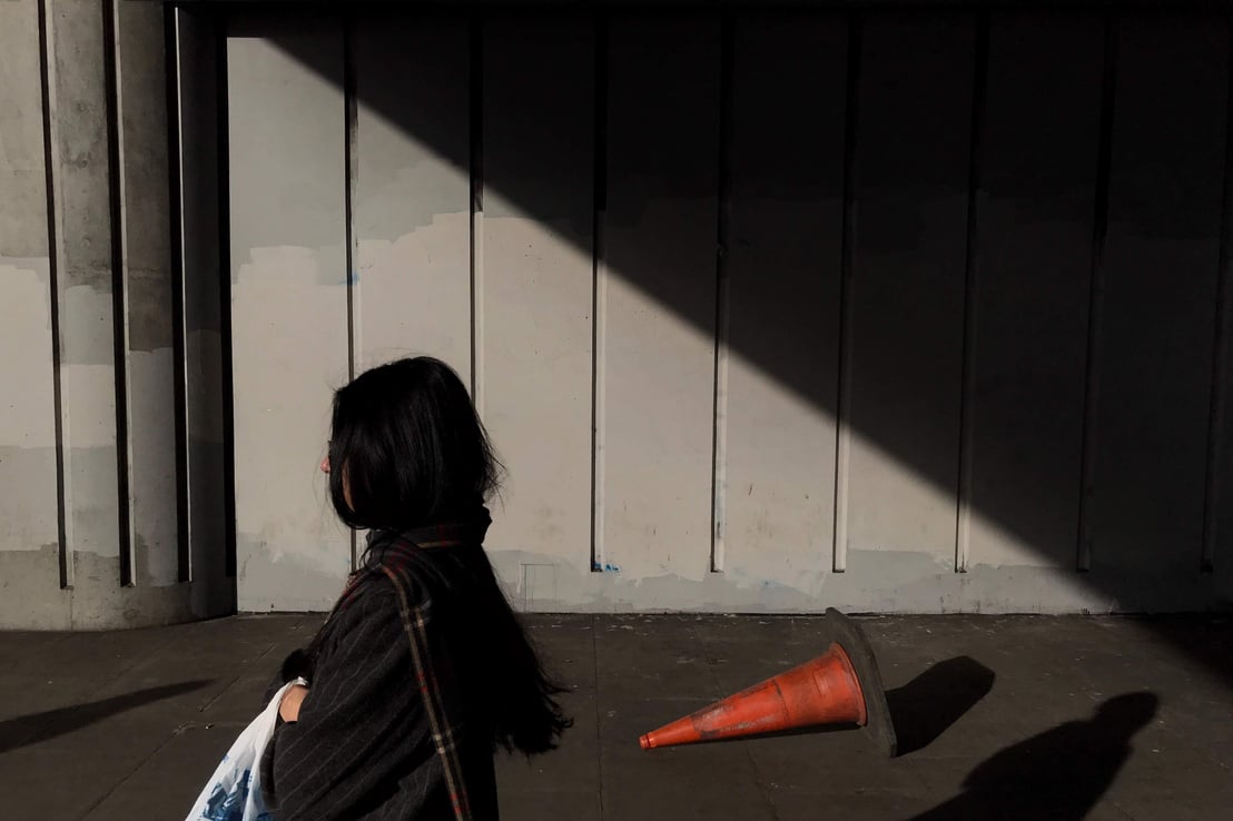 Moody street photograph a person is standing in front of an orange cone.